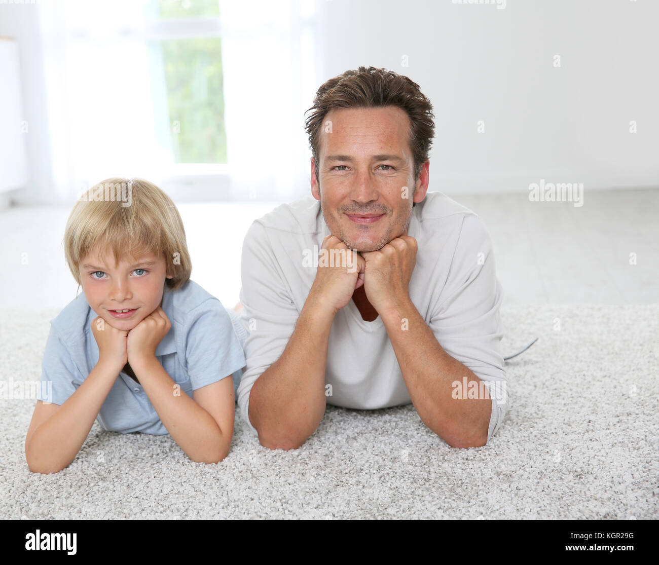 Padre e figlio la posa su un tappeto a casa Foto Stock