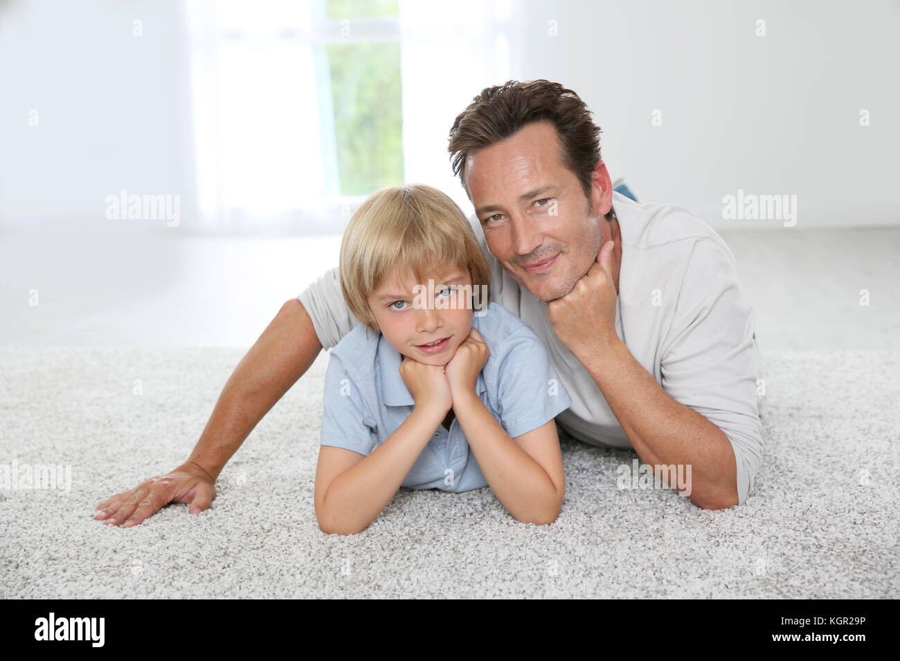 Padre e figlio la posa su un tappeto a casa Foto Stock