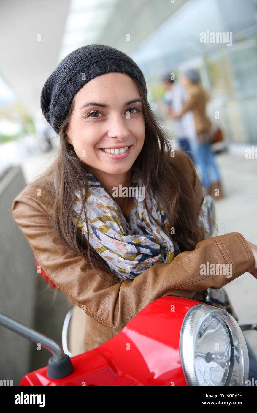 Attraente giovane donna seduta su red scooter Foto Stock