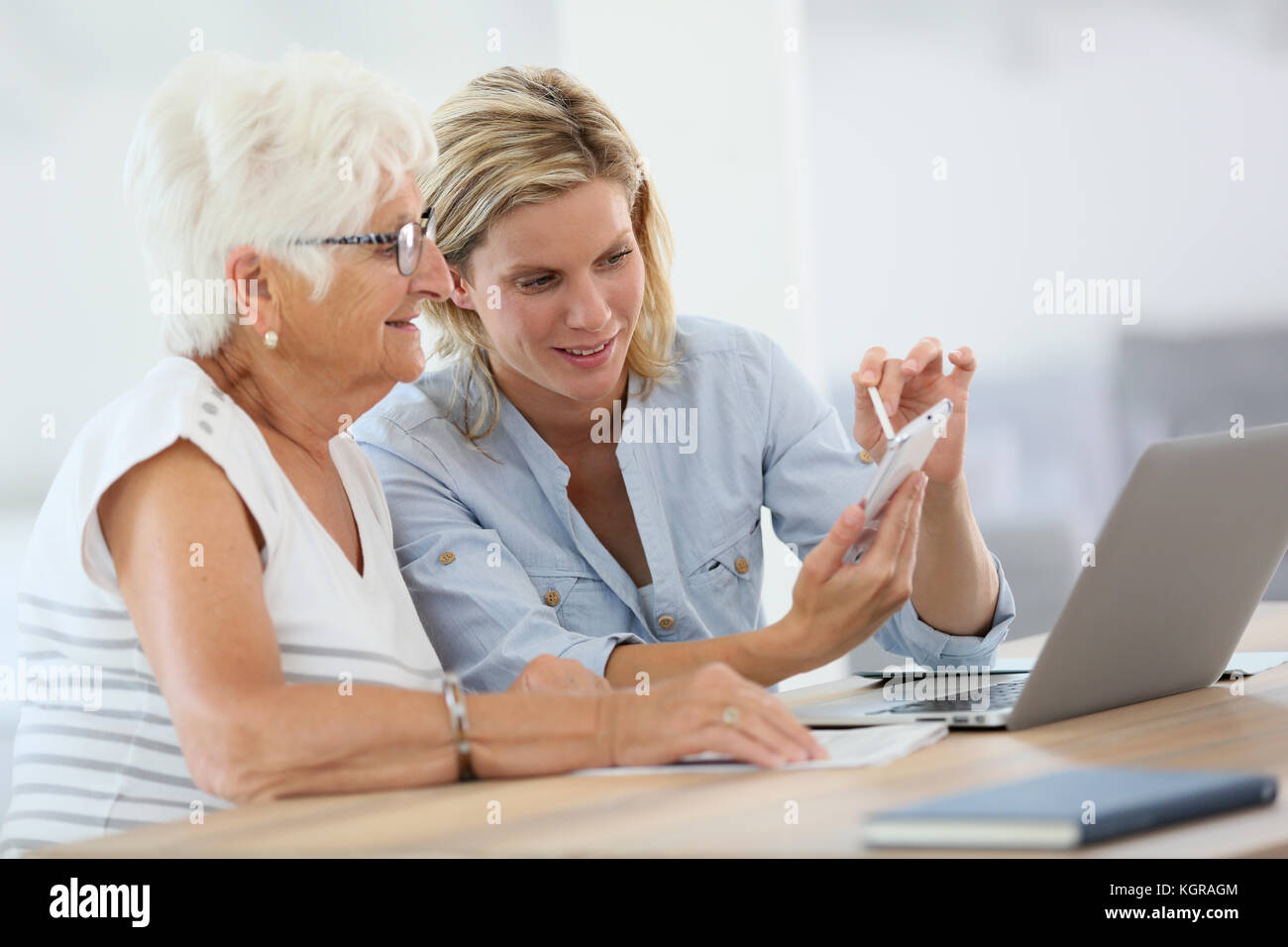 Homehelp con donna anziana utilizza lo smartphone Foto Stock