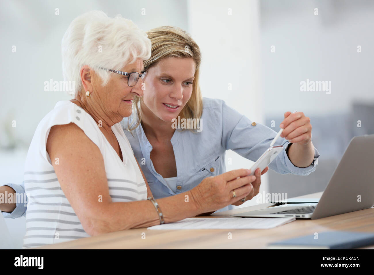 Homehelp con donna anziana utilizza lo smartphone Foto Stock