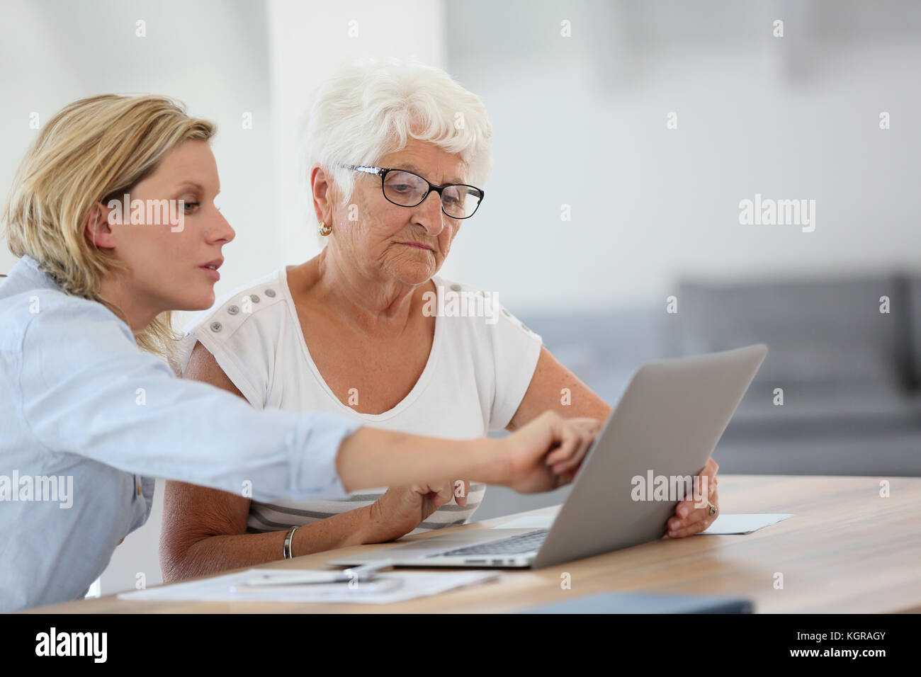 Homecarer con donna anziana utilizzando il computer portatile Foto Stock