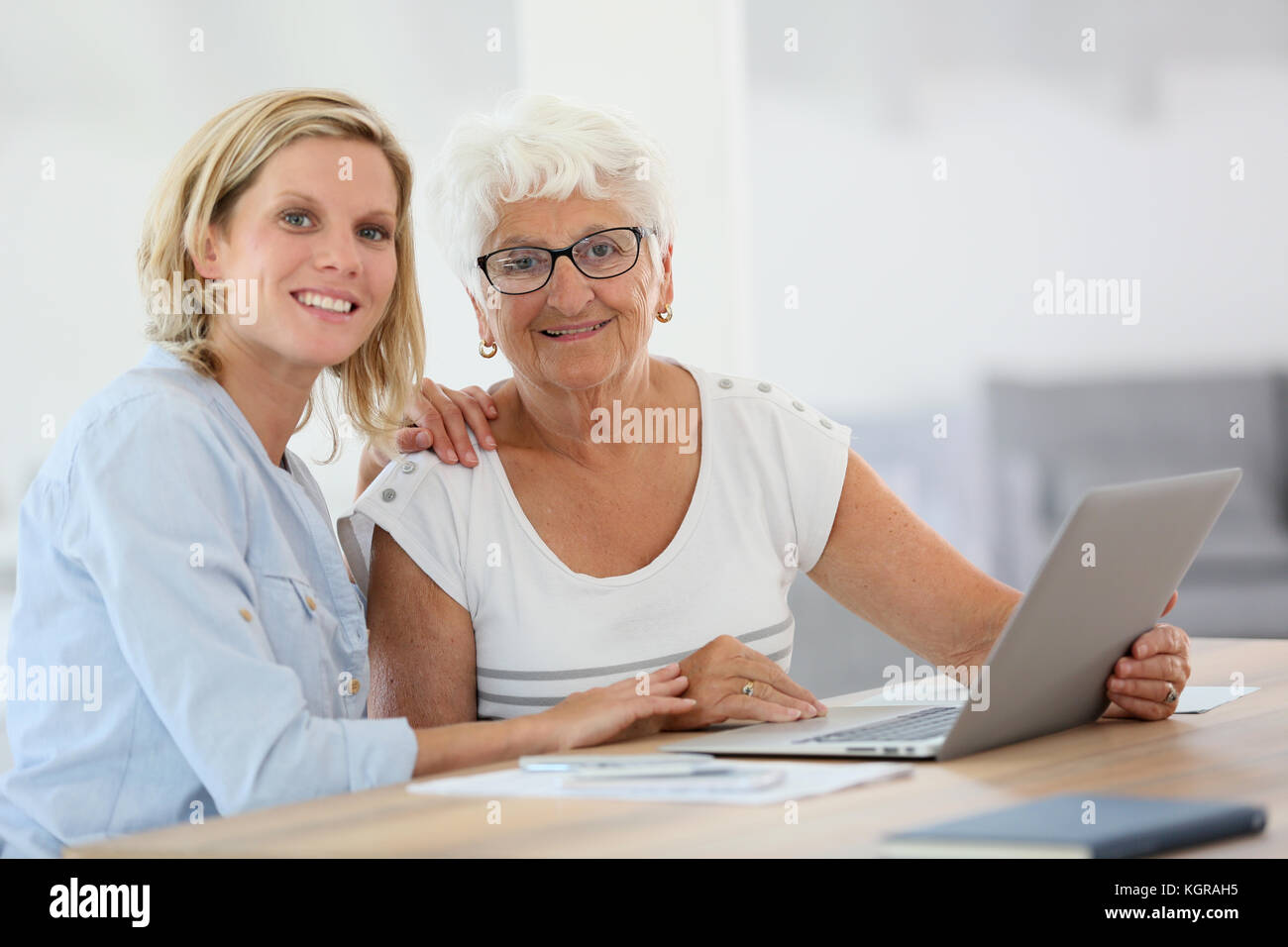 Homecarer con donna anziana utilizzando il computer portatile Foto Stock