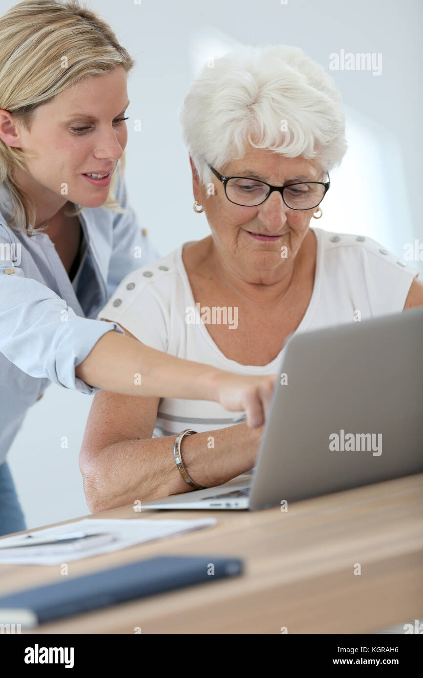 Homecarer con donna anziana utilizzando il computer portatile Foto Stock