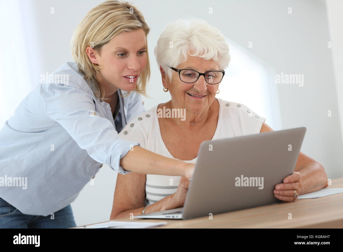 Homecarer con donna anziana utilizzando il computer portatile Foto Stock