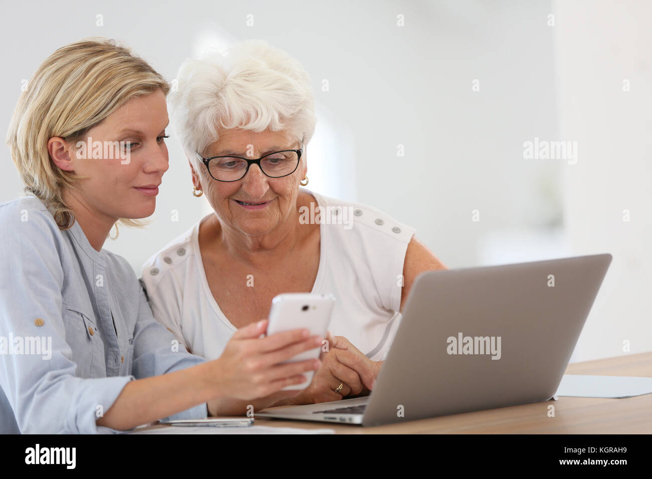 Homehelp con donna anziana utilizza lo smartphone Foto Stock