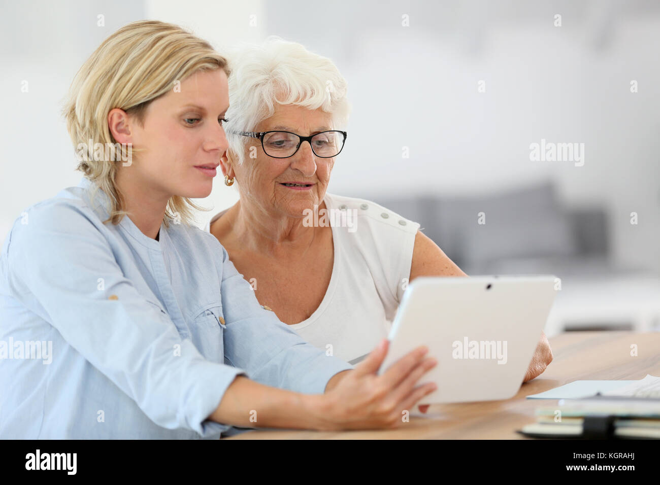 Homehelp con donna anziana con tavoletta digitale Foto Stock