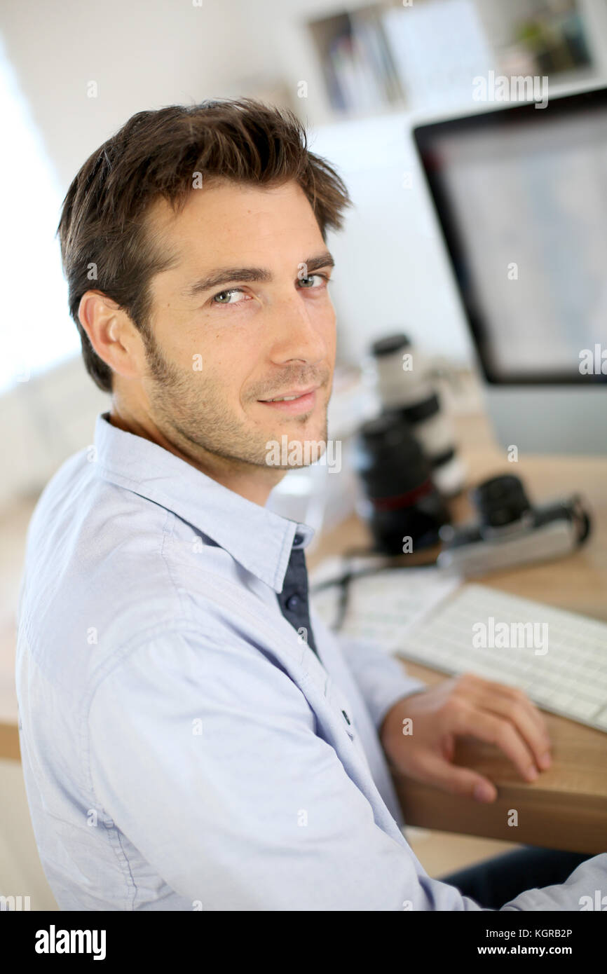 Fotografo in ufficio a lavorare sul computer desktop Foto Stock