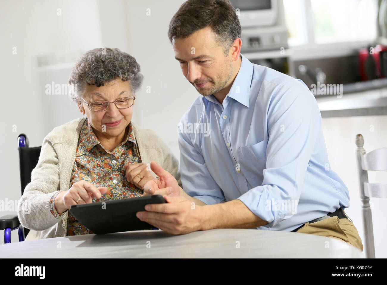 L'uomo con la donna anziana con tavoletta digitale Foto Stock