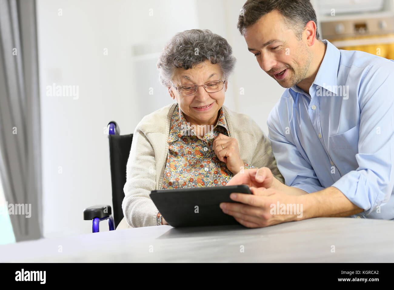 L'uomo con la donna anziana con tavoletta digitale Foto Stock