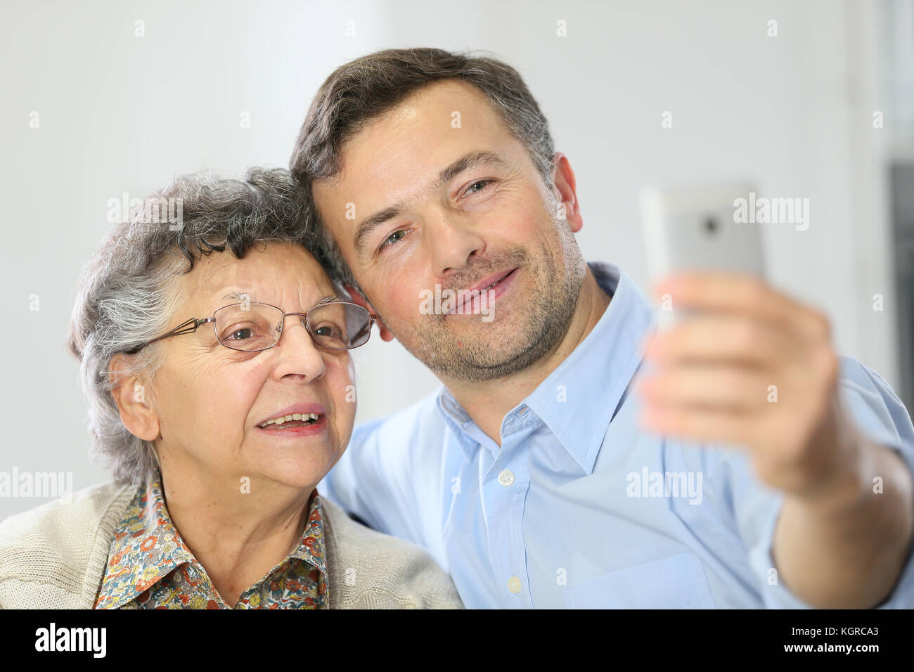 Donna anziana con figlio facendo selfy foto con lo smartphone Foto Stock