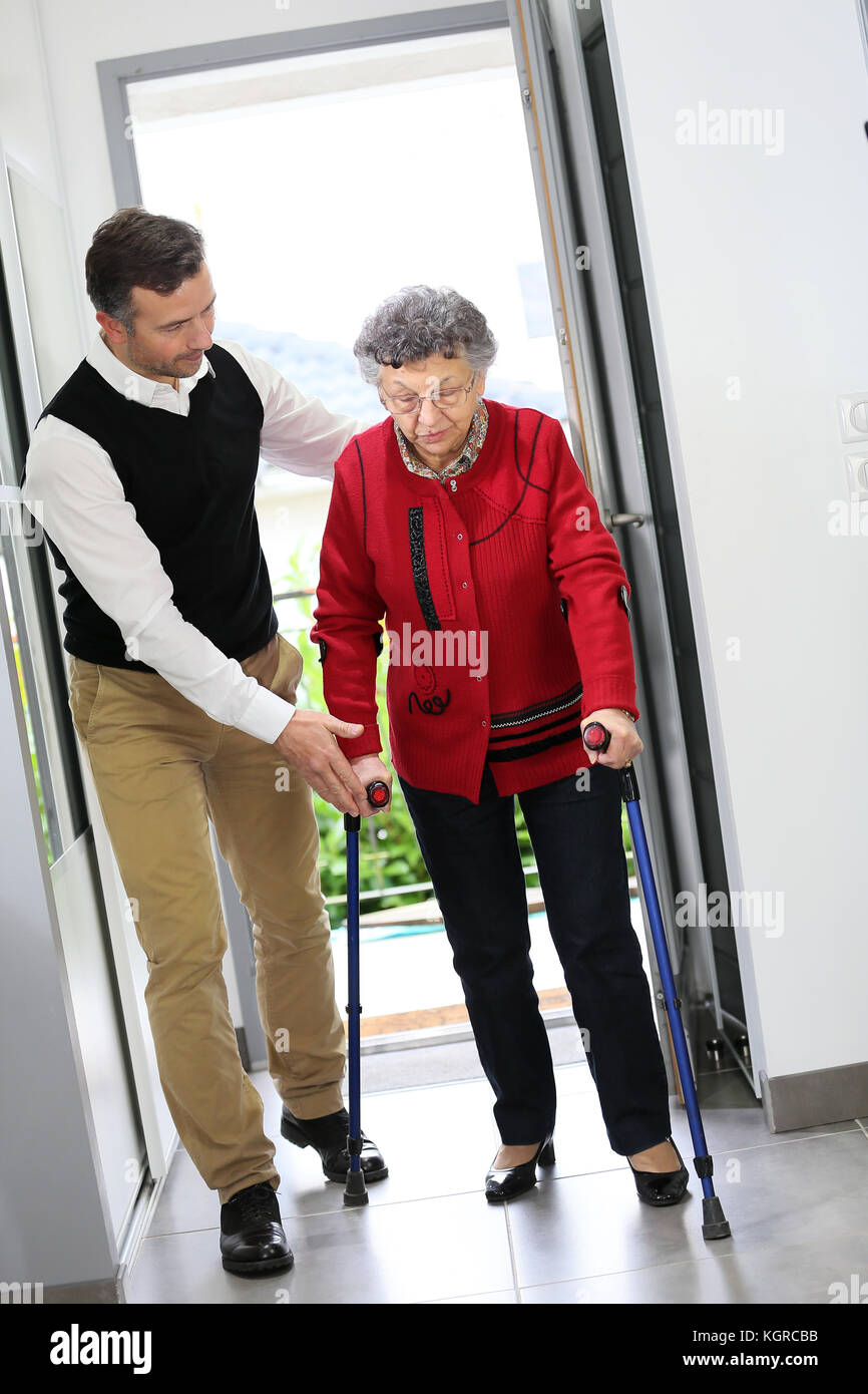 L'uomo aiutando donna anziana con le stampelle Foto Stock
