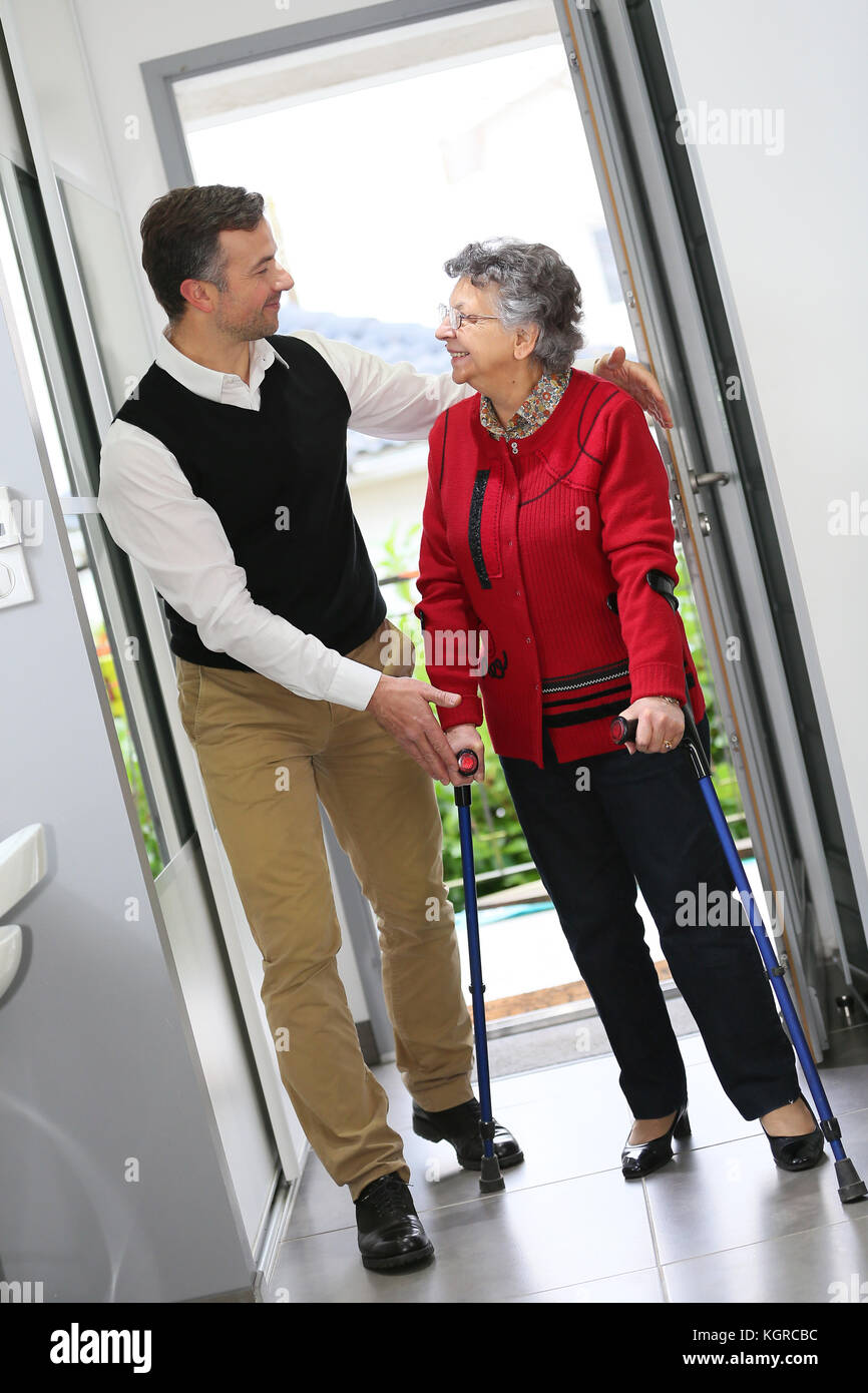 L'uomo aiutando donna anziana con le stampelle Foto Stock