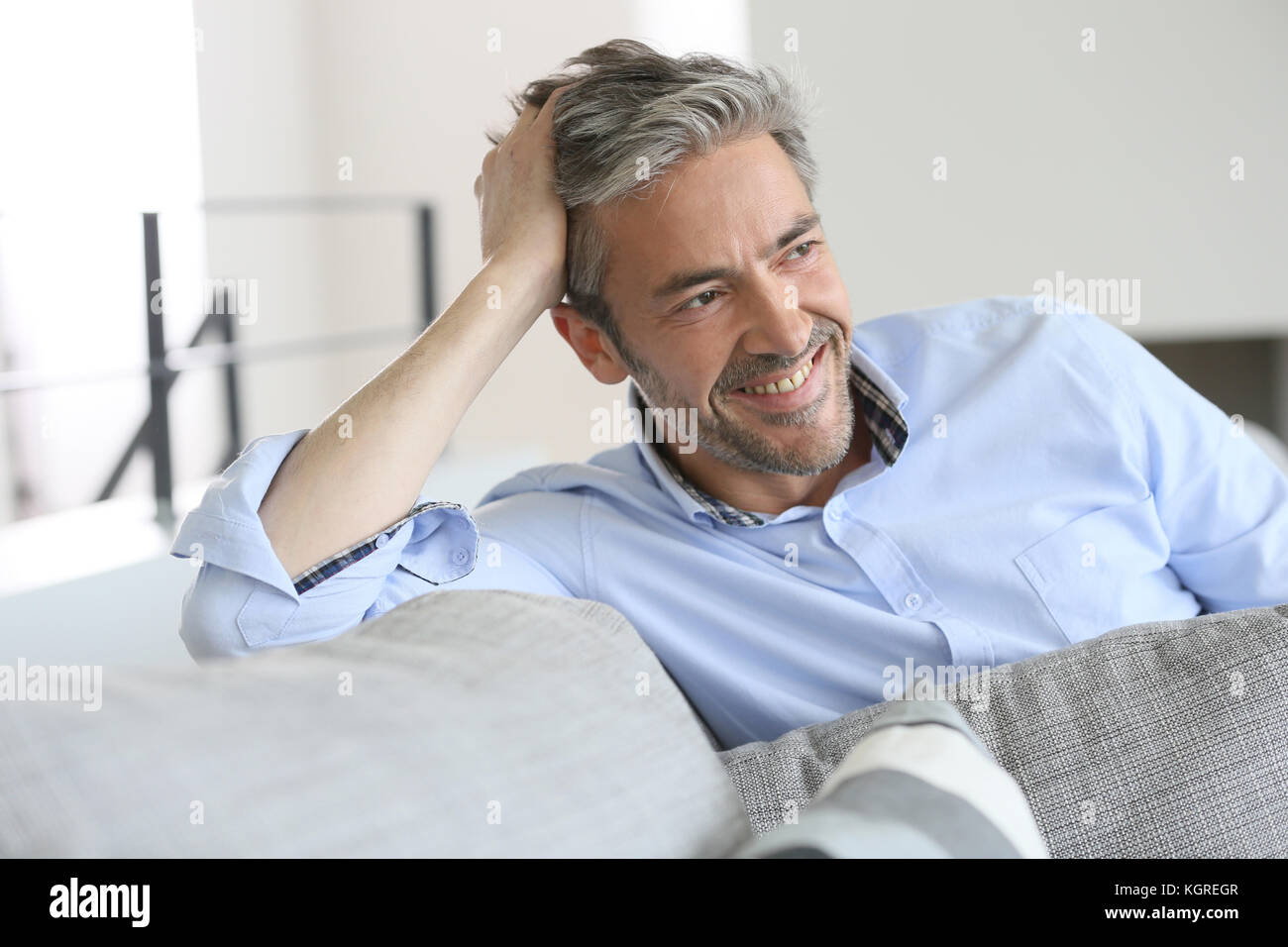 Sorridente bello 45-anno-vecchio uomo in un momento di relax a casa Foto Stock