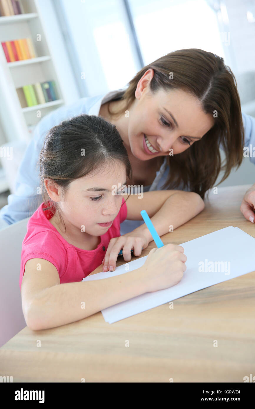 Scuola della bambina con la madre imparare a scrivere Foto Stock