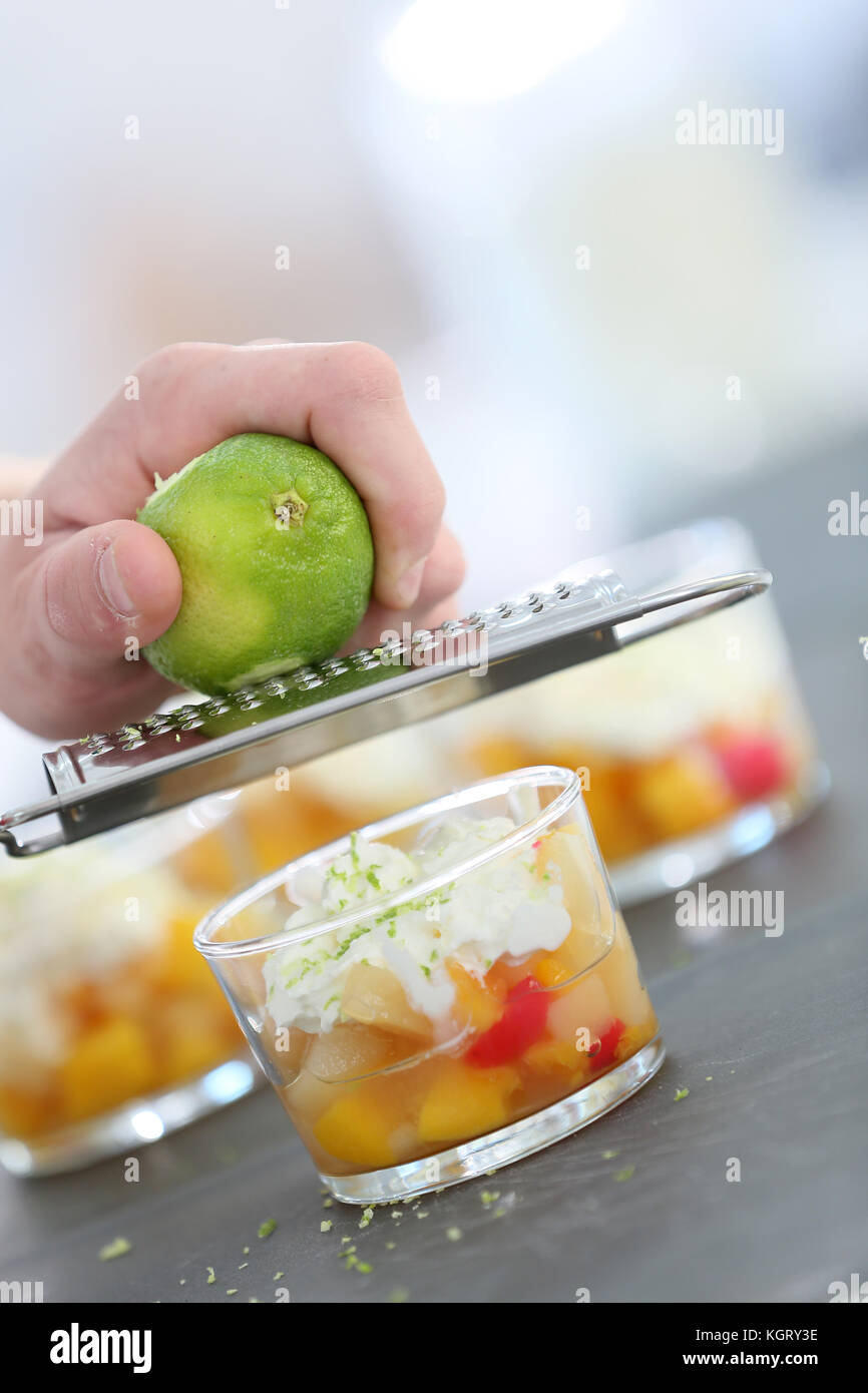 Cuocere strofinando la scorza di limone con grattugia su dessert Foto Stock