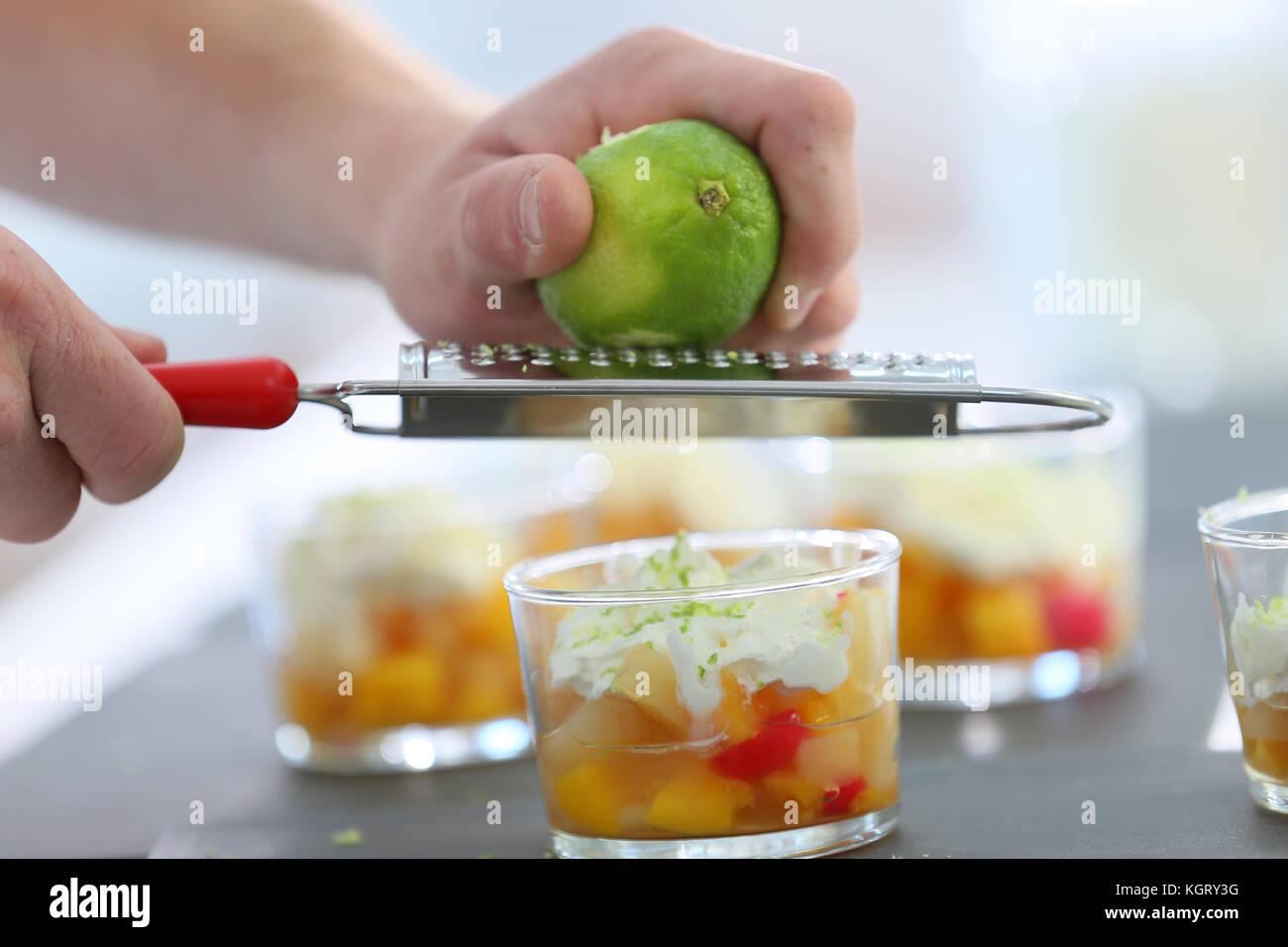 Cuocere strofinando la scorza di limone con grattugia su dessert Foto Stock