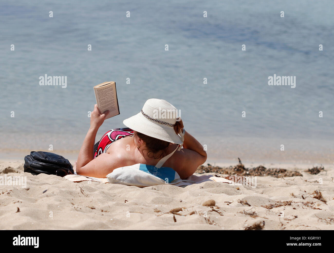 Le donne sole e legge un libro sulla spiaggia Arenal in primavera quando la stagione turistica inizia a. Arenal è un ex villaggio di pescatori, è eminentemente t Foto Stock