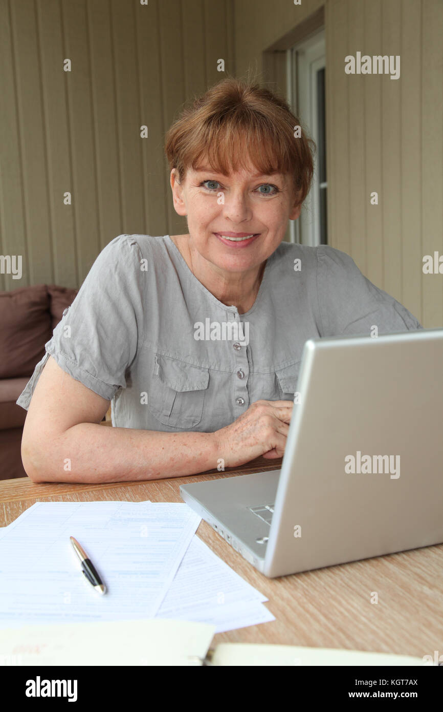Senior donna la compilazione con l aiuto di internet Foto Stock