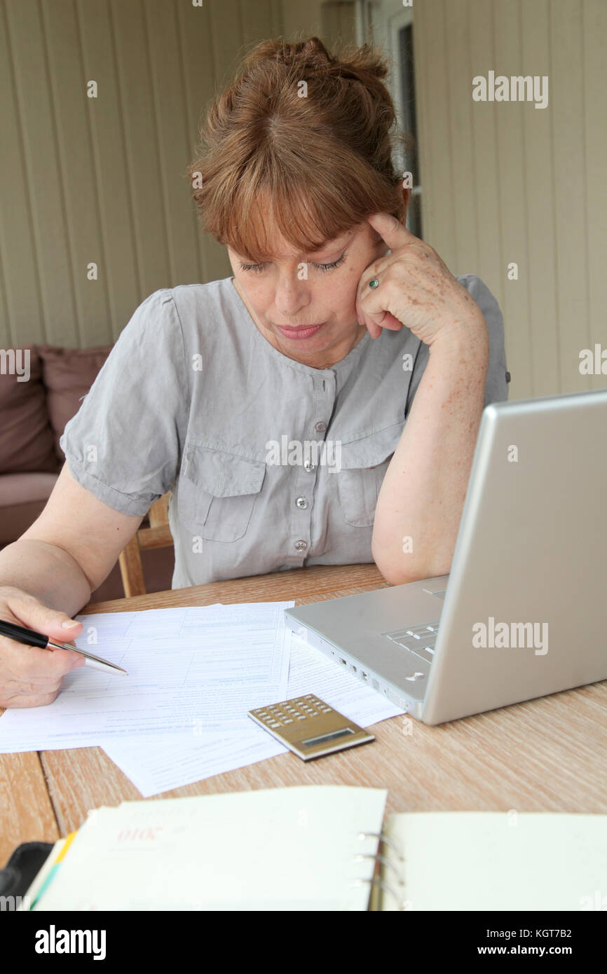 Senior donna la compilazione con l aiuto di internet Foto Stock