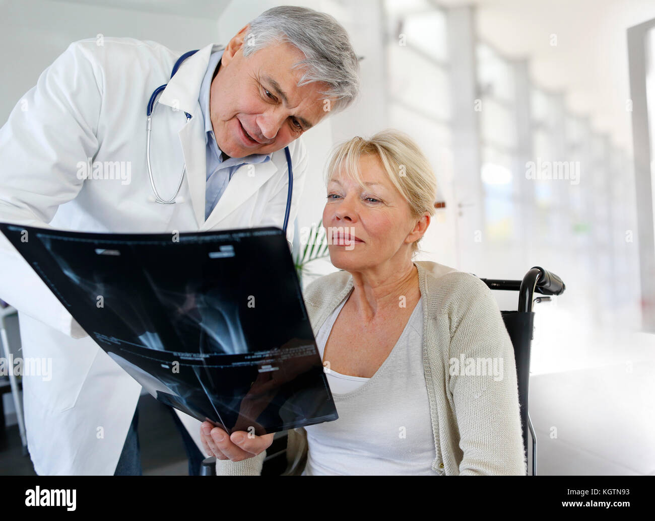 Il chirurgo che mostra x-ray risultato alla donna in sedia a rotelle Foto Stock