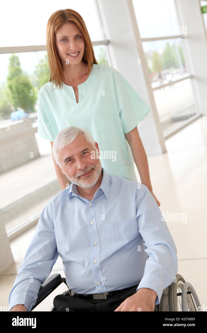L'infermiera aiutando senior uomo in sedia a rotelle Foto Stock