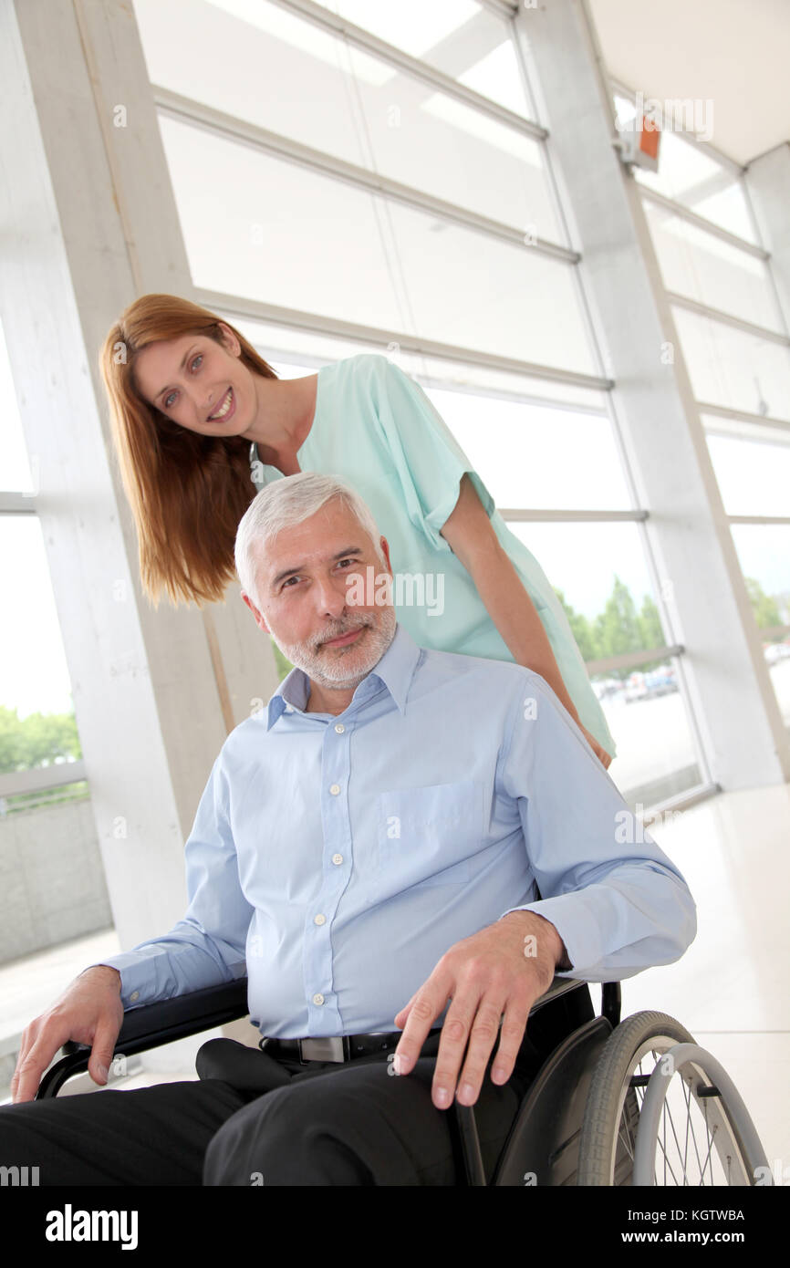 L'infermiera aiutando senior uomo in sedia a rotelle Foto Stock