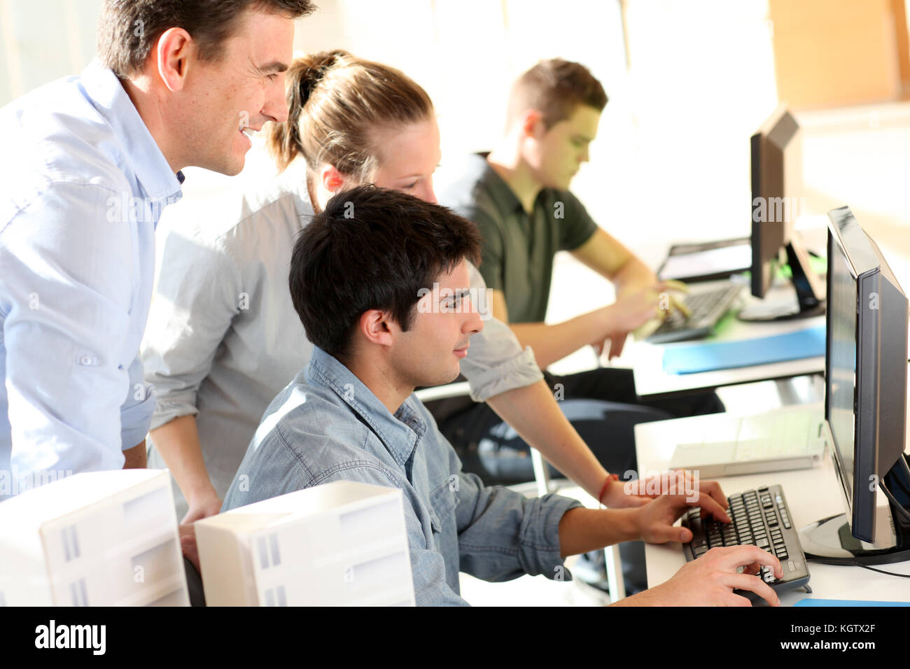 Gli studenti con insegnante nella parte anteriore del computer desktop Foto Stock