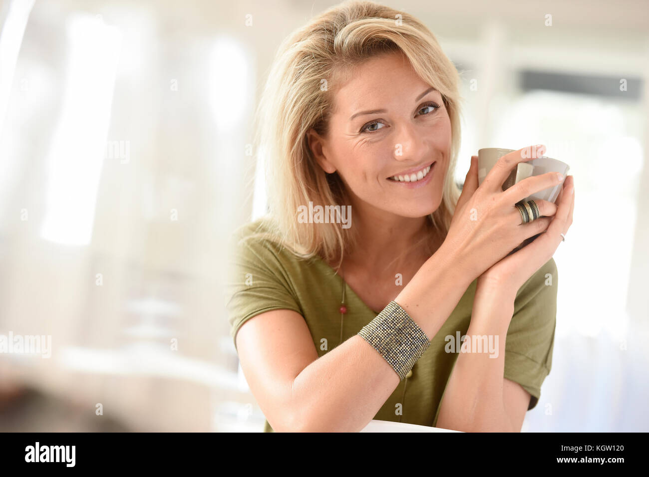 Attraente bionda donna di mezza età fustellatura tè caldo Foto Stock