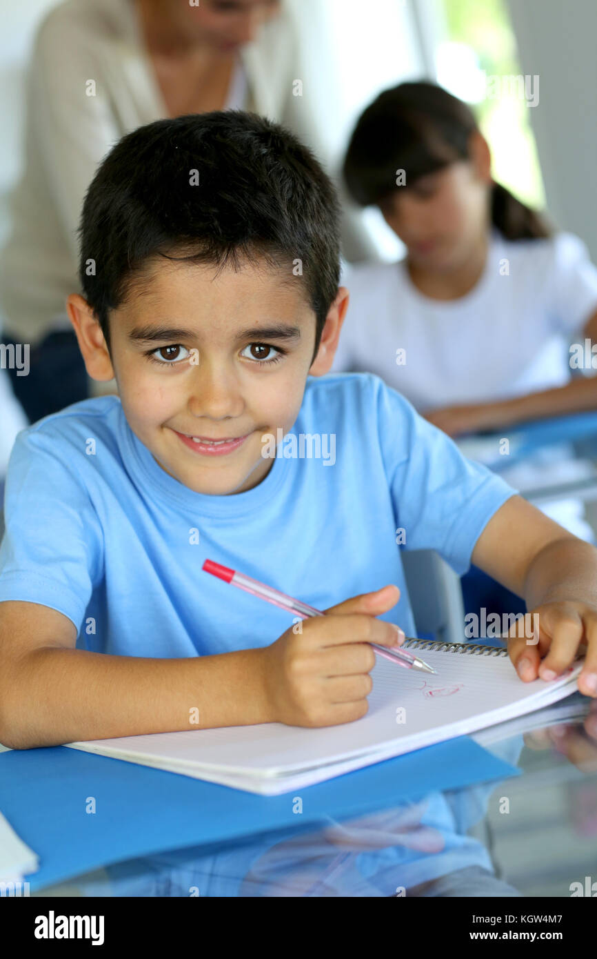 Ritratto di smilng giovane ragazzo seduto in aula Foto Stock