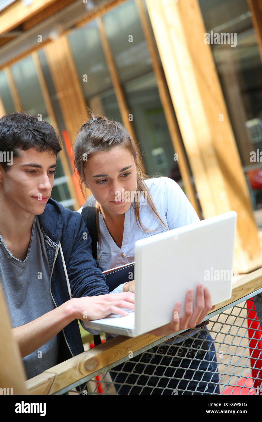 Gli adolescenti lavorando su laptop nel campus della scuola Foto Stock