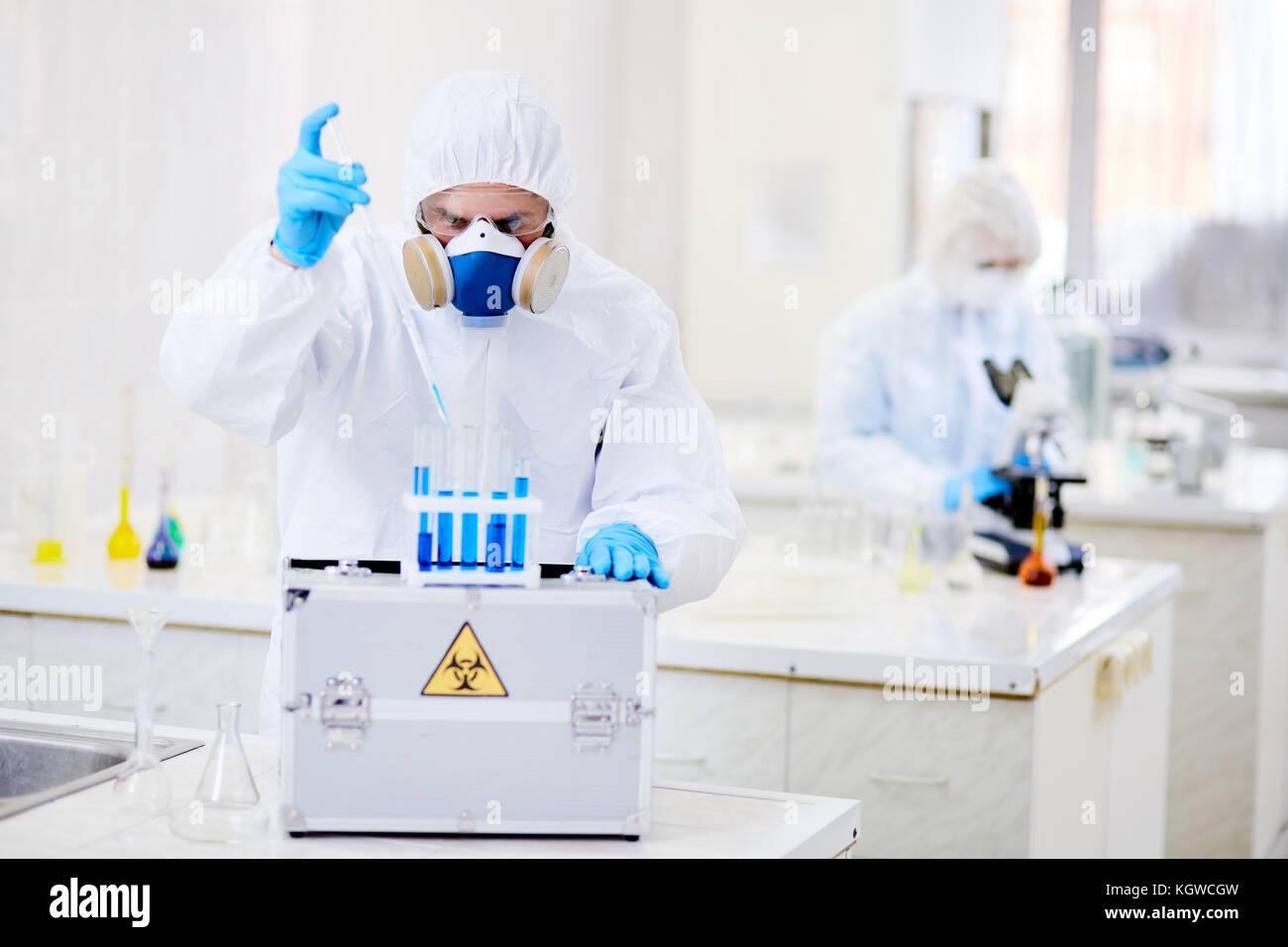 Scienziato che rilascia la sostanza liquida nel pallone con liquido tossico Foto Stock