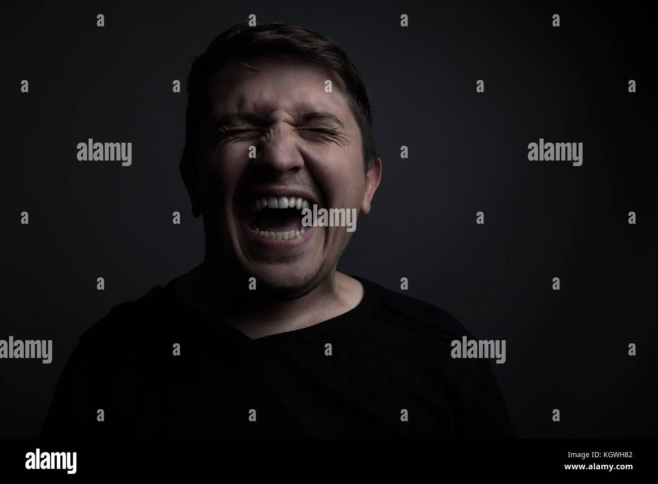 Ritratto di uomo yell di dolore di fronte a uno sfondo grigio Foto Stock