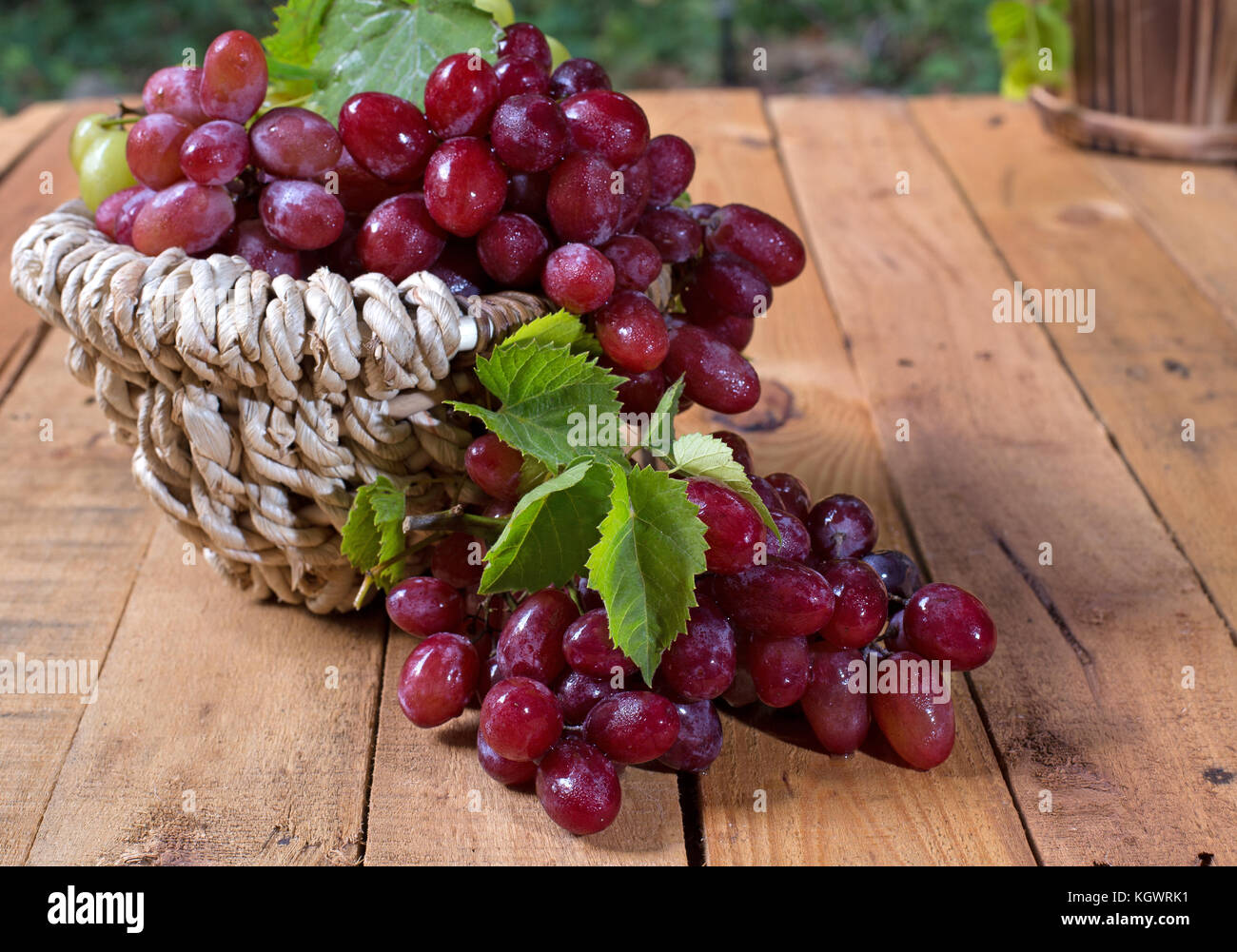 Cesto di uva rossa su una superficie in legno Foto Stock