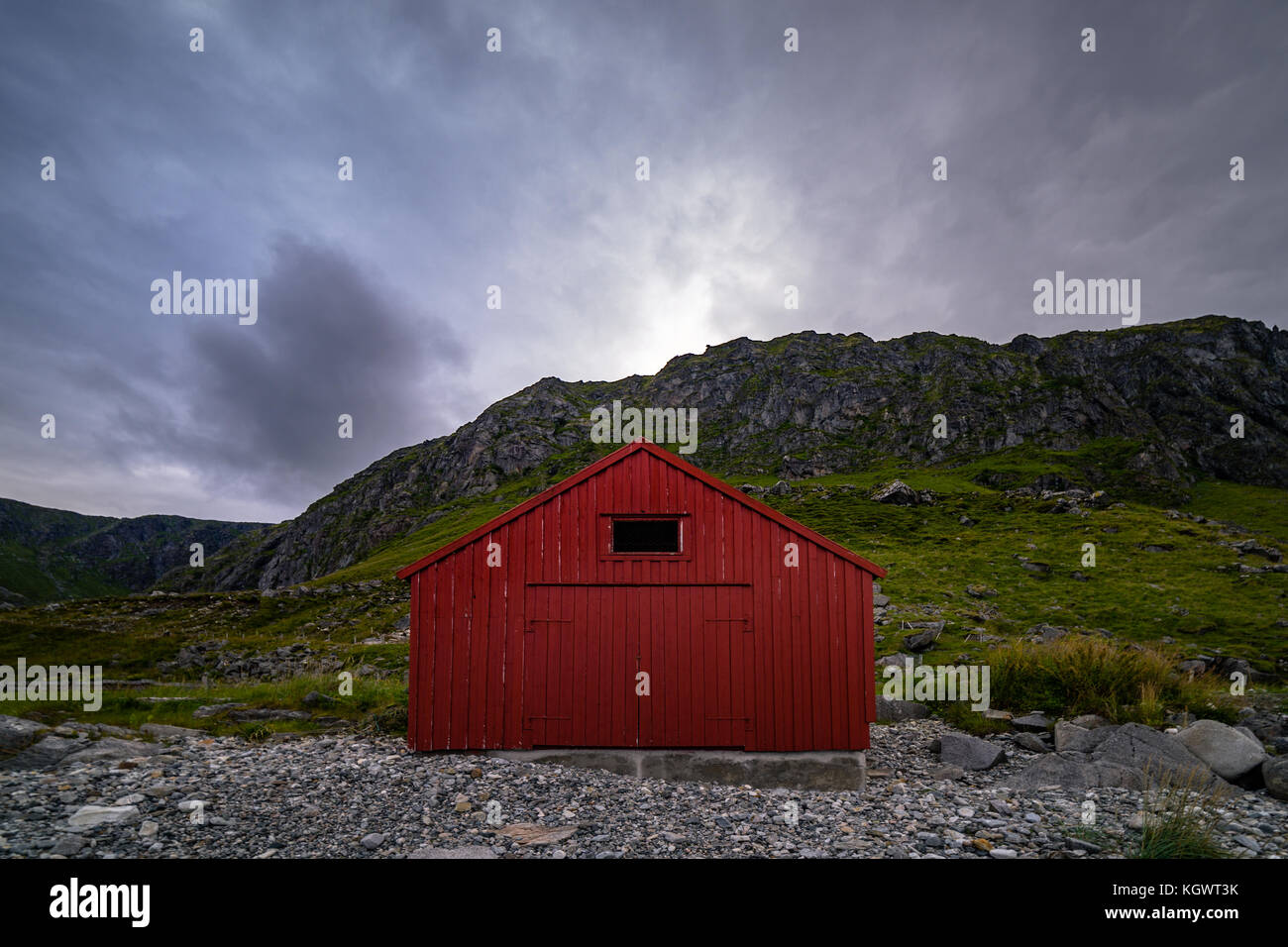 Tradizionale in rosso norvegese casa di pescatori con le montagne sullo sfondo. Foto Stock