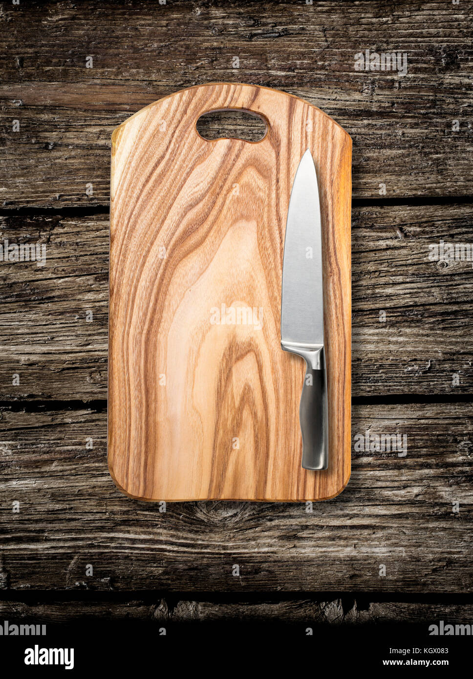 Svuotare tagliere con un forte spelucchino dritto su un distressed grunge tavolo di legno in una cucina rustica, Foto Stock