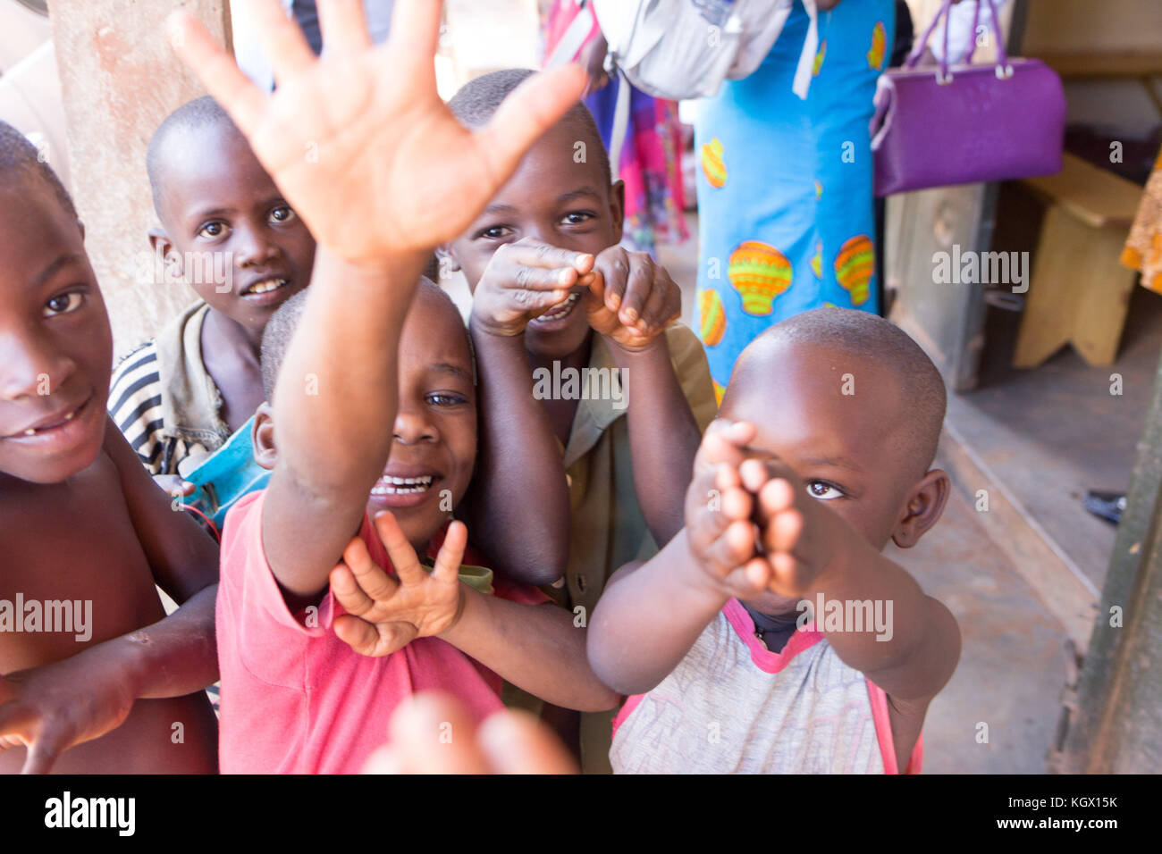 Un mazzetto di random bambini ugandesi in strada a ridere, sorridente, agitando e divertirsi nella parte anteriore della fotocamera. Foto Stock