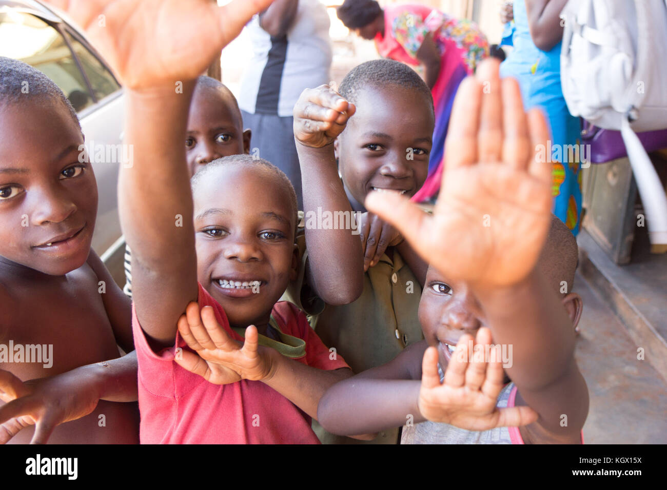 Un mazzetto di random bambini ugandesi in strada a ridere, sorridente, agitando e divertirsi nella parte anteriore della fotocamera. Foto Stock