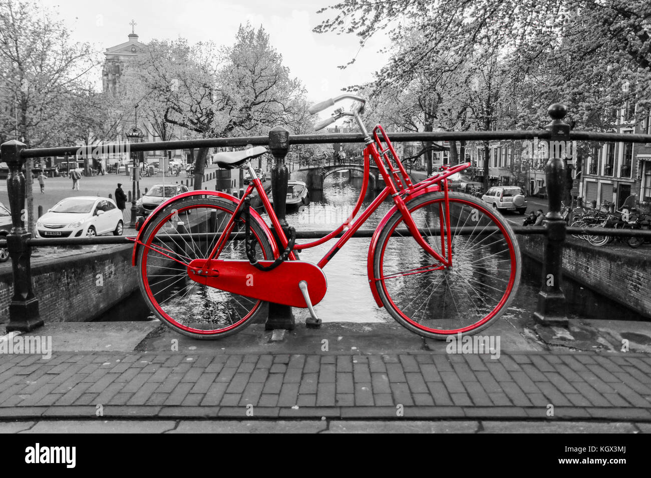 Una foto di un solitario red bici sul ponte sul canale di Amsterdam. Lo sfondo è bianco e nero. Foto Stock