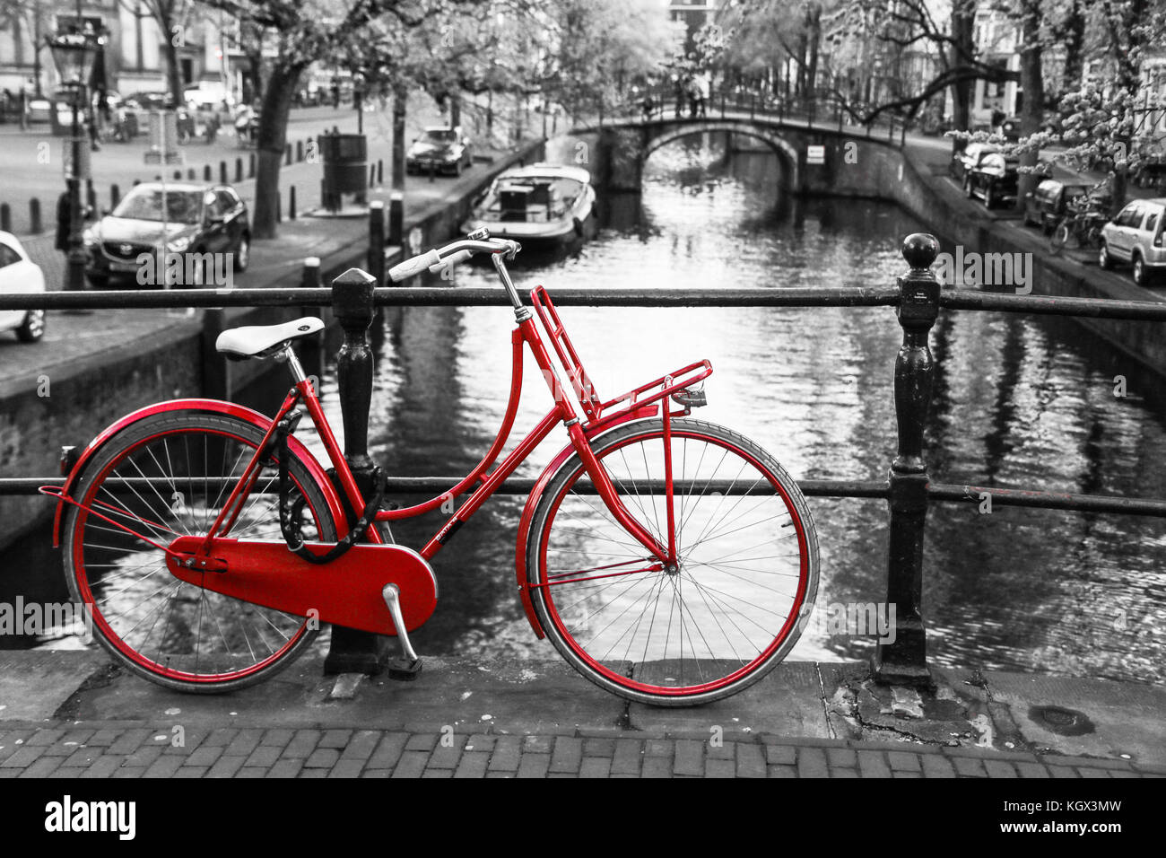 Una foto di un solitario red bici sul ponte sul canale di Amsterdam. Lo sfondo è bianco e nero. Foto Stock