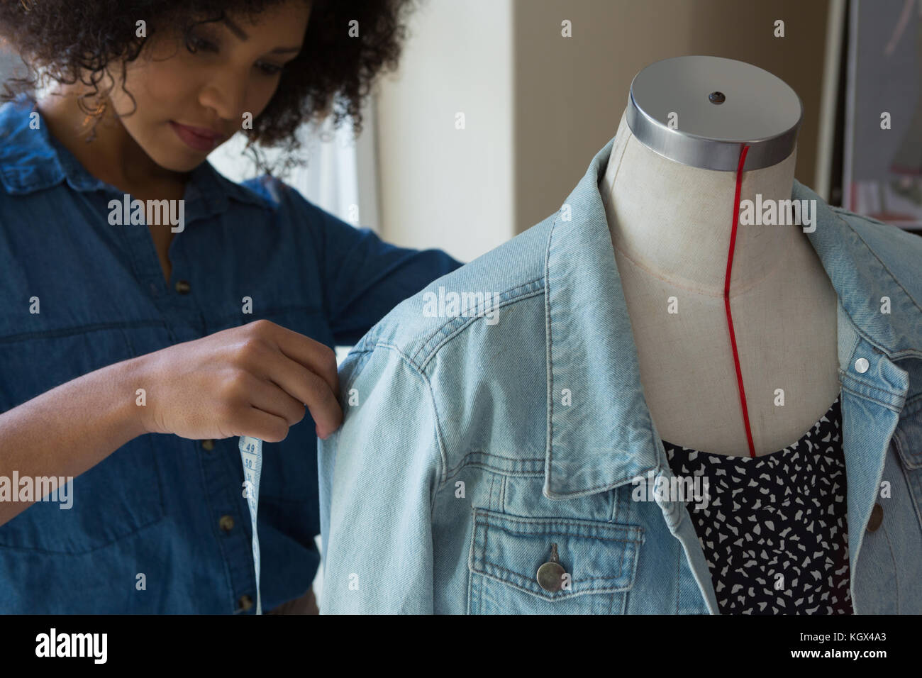 Designer femmina misurando la lunghezza di denim su manichino a casa Foto Stock