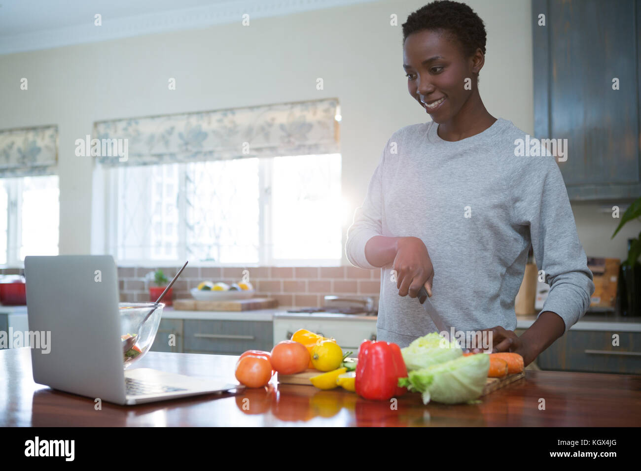 Bella donna di apprendimento ricetta alimentare dal laptop in cucina Foto Stock