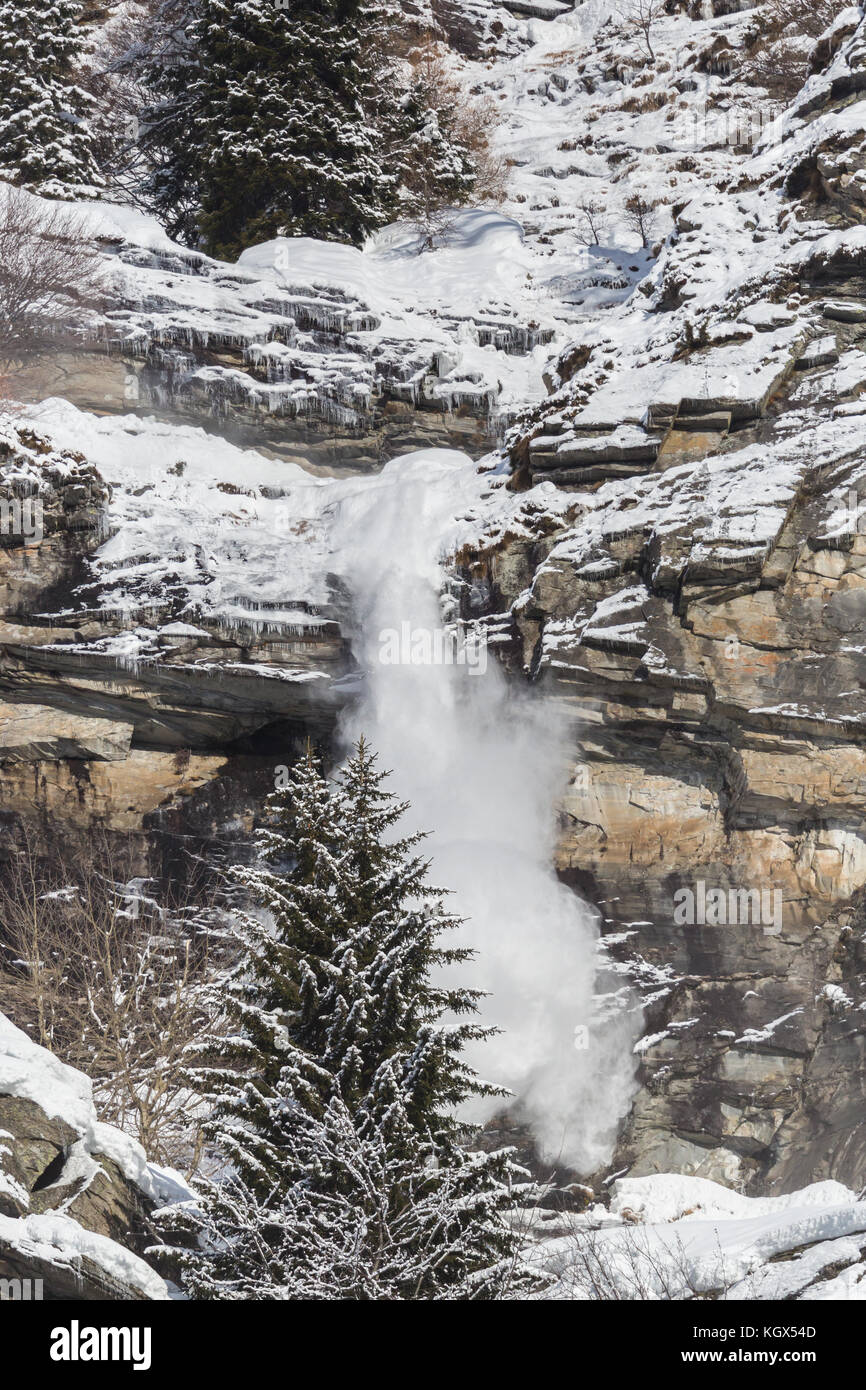 Neve naturale scorrere a valanga a parete di roccia cliff, inverno, albero, sunshine Foto Stock