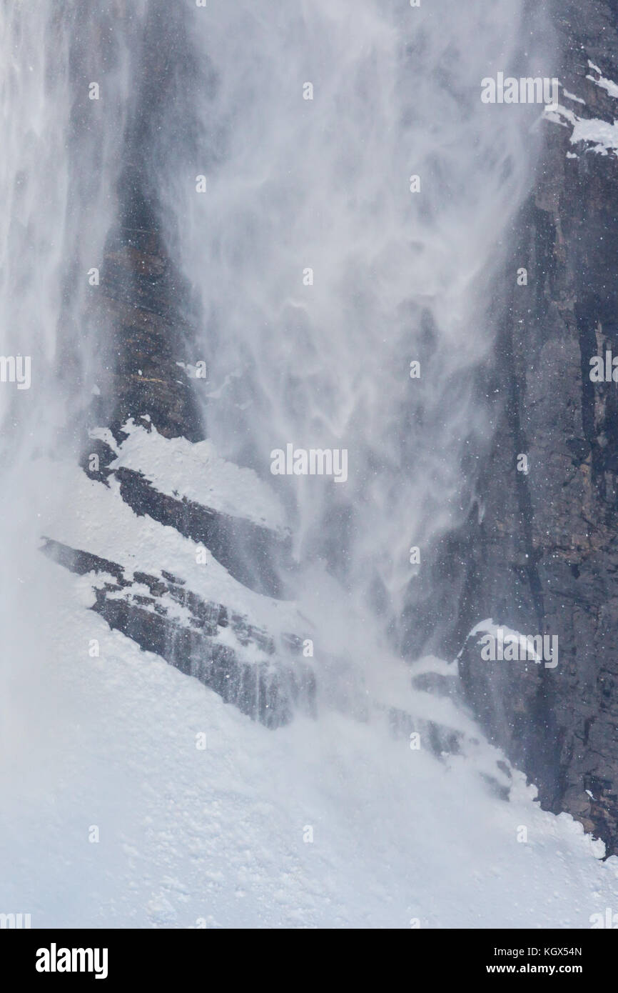 Neve naturale scorrere in corrispondenza di cliff in inverno in montagna con rocce Foto Stock
