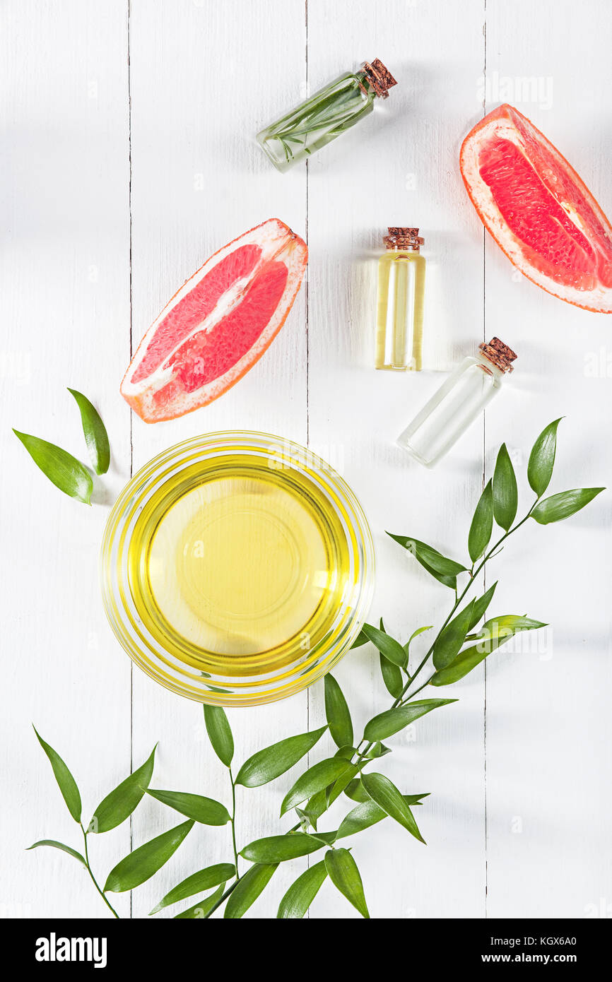 Olio essenziale in una bottiglia di vetro con fresche, succosa di pompelmo e foglie verdi-trattamento di bellezza. Foto Stock