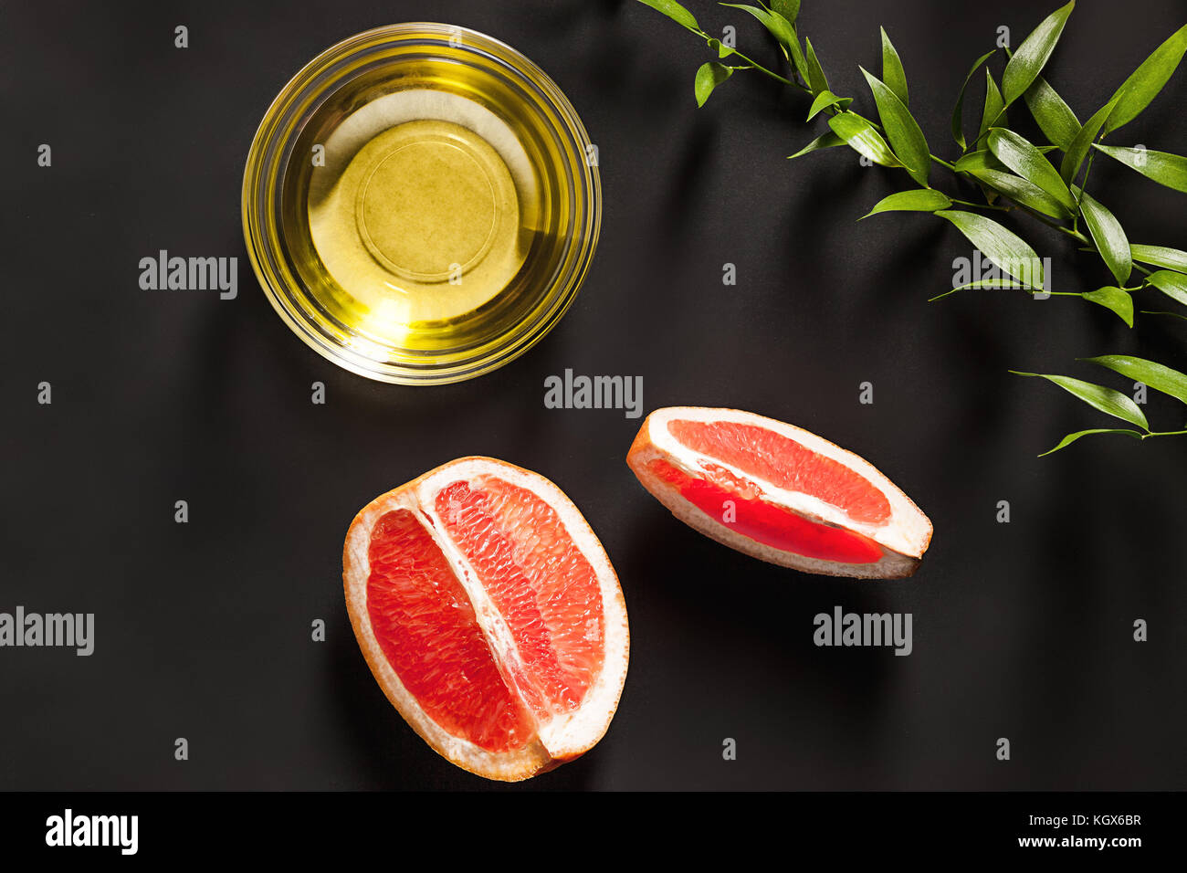 Olio essenziale in una bottiglia di vetro con fresche, succosa di pompelmo e foglie verdi-trattamento di bellezza. Foto Stock