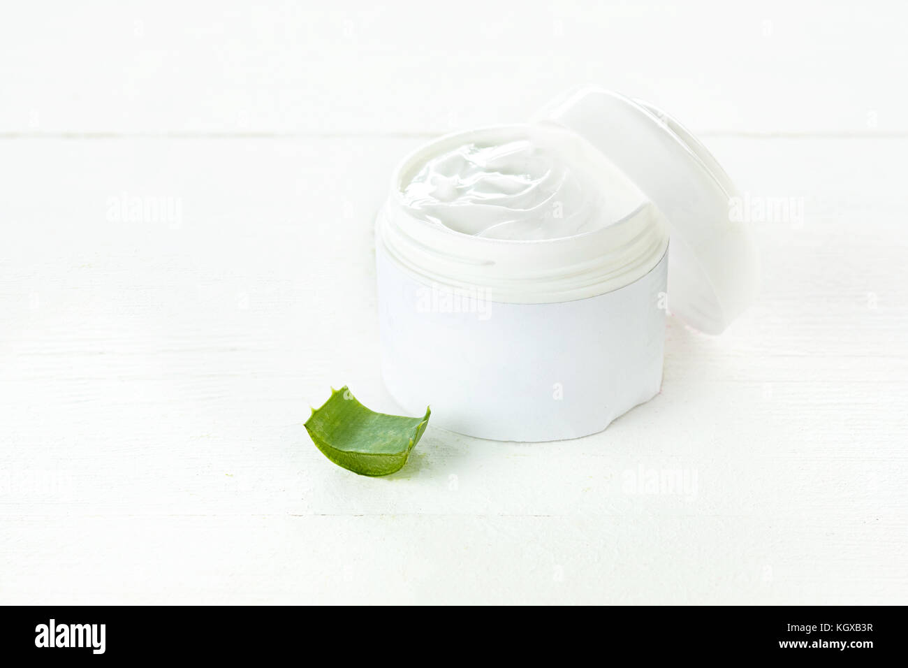Aperto il contenitore in plastica con panna e aloe su uno sfondo bianco. Foto Stock