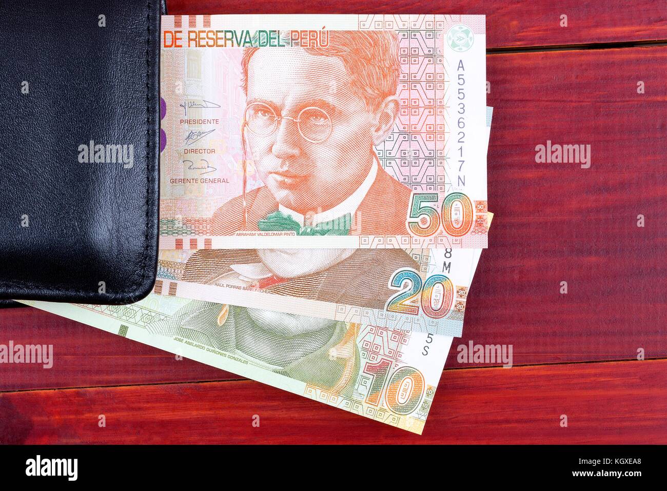 Denaro peruviana nel portafoglio nero su uno sfondo di legno Foto Stock