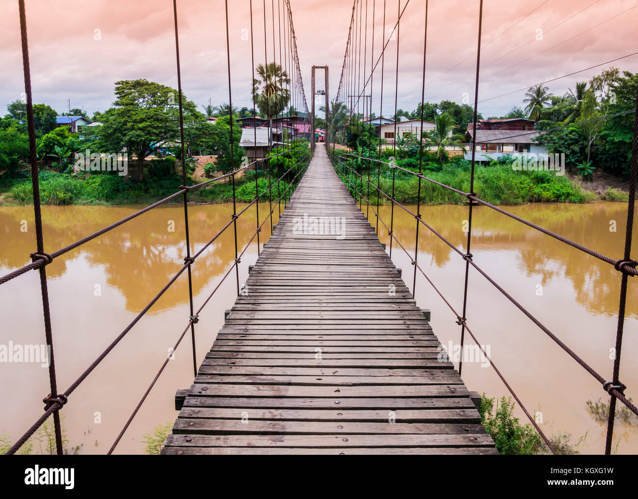 Corda sospensione ponte su un fiume in piena al tramonto, Thailandia Foto Stock