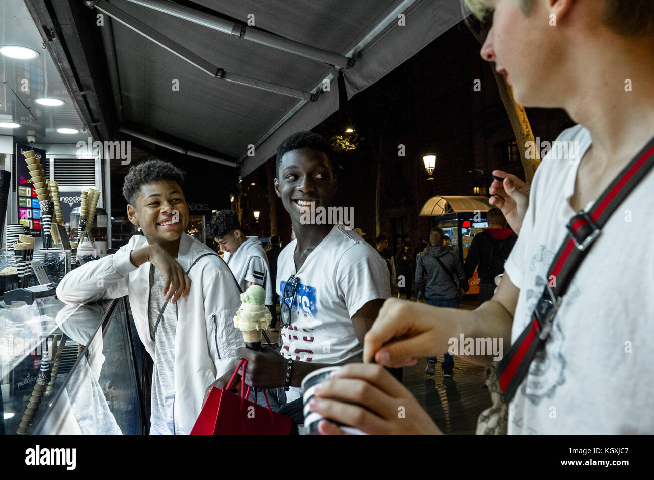 Gioiosa giovani uomini acquisto di gelato da un negozio all'aperto sulla Rambla, Barcelona, Spagna, Foto Stock
